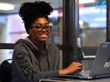 Image of a woman using a laptop computer that links to Admissions application.